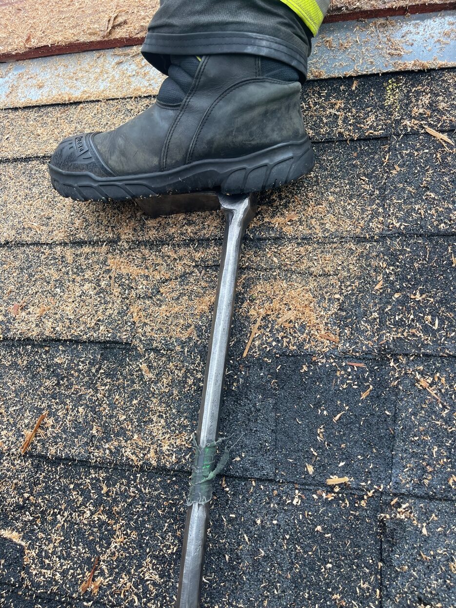 Firefighter standing on a narrow halligan bar pick during roof operations — unstable and dangerous