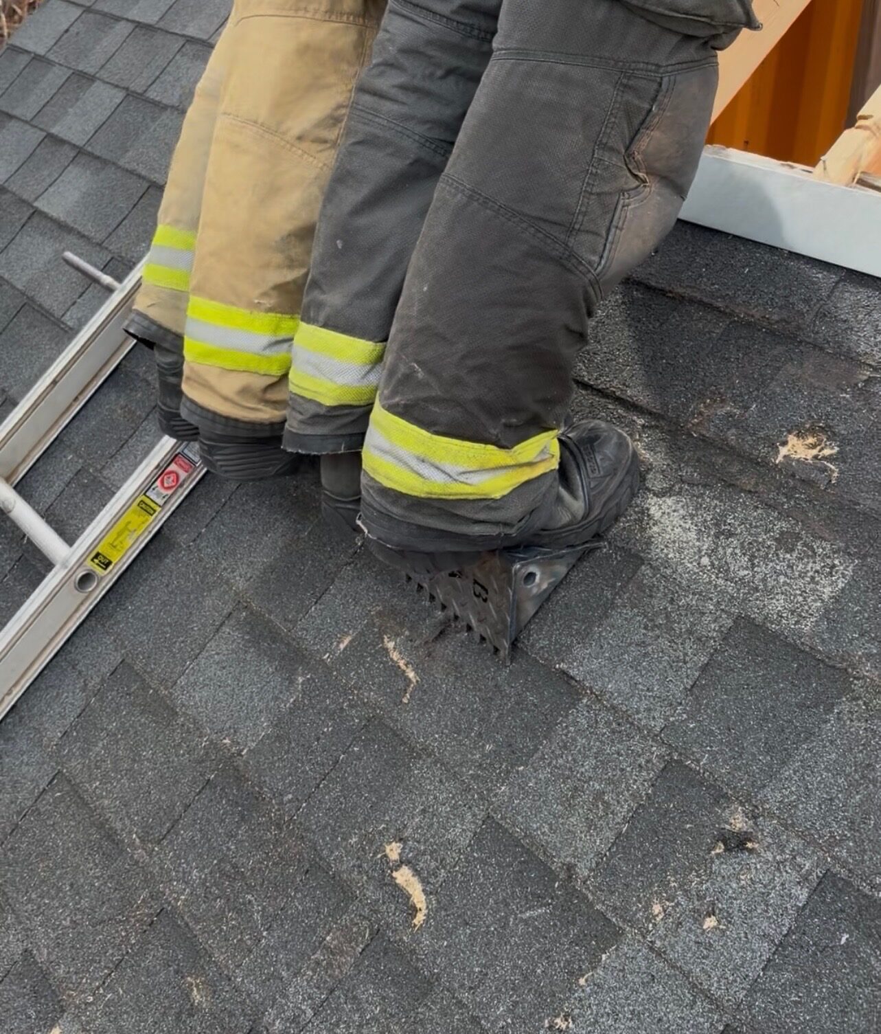Close-up of two firefighter boots on the Rash Bar showing the teeth gripping the roof shingles