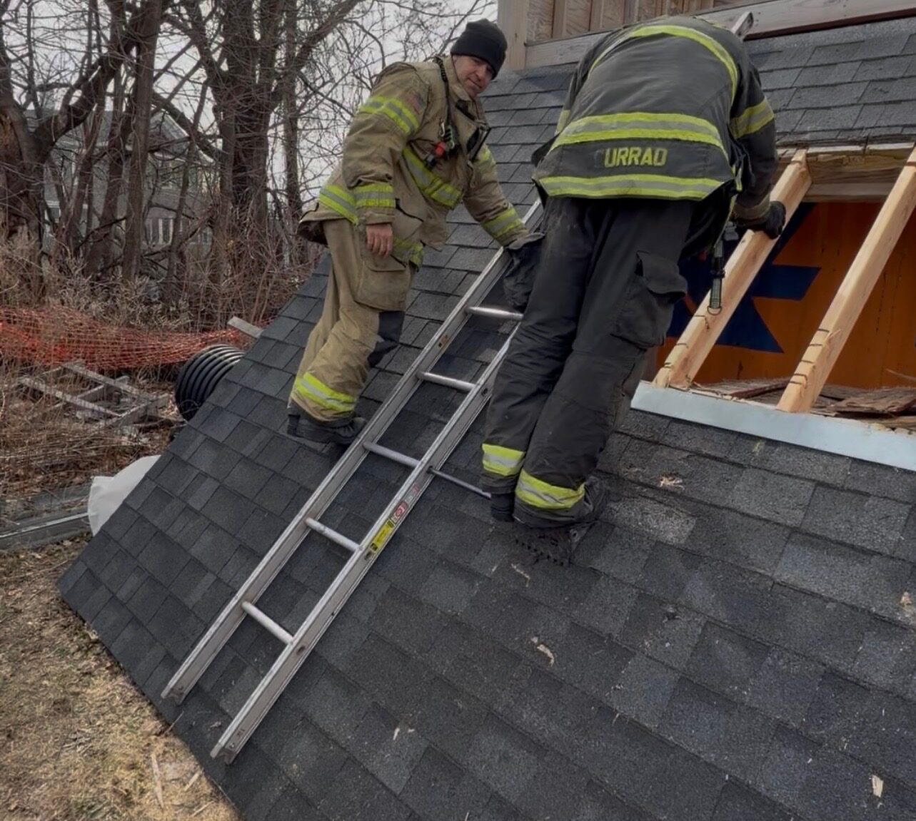 Two firefighters working together on a steep roof during ventilation training